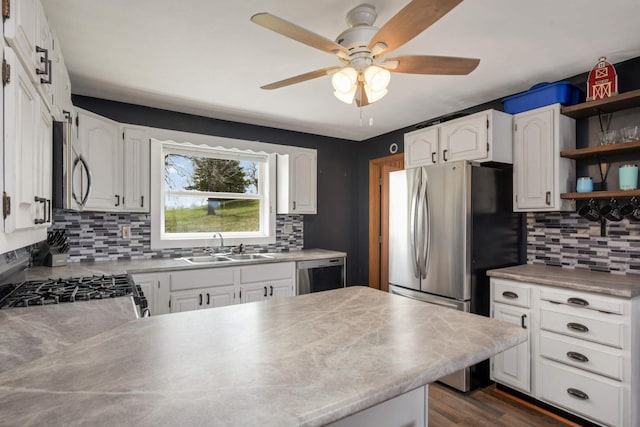 kitchen with a sink, ceiling fan, white cabinetry, backsplash, and appliances with stainless steel finishes