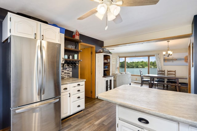 kitchen with open shelves, light countertops, dark wood-type flooring, freestanding refrigerator, and ceiling fan with notable chandelier