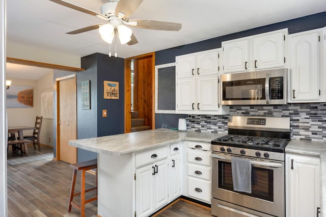 kitchen featuring white cabinets, a peninsula, tasteful backsplash, appliances with stainless steel finishes, and ceiling fan