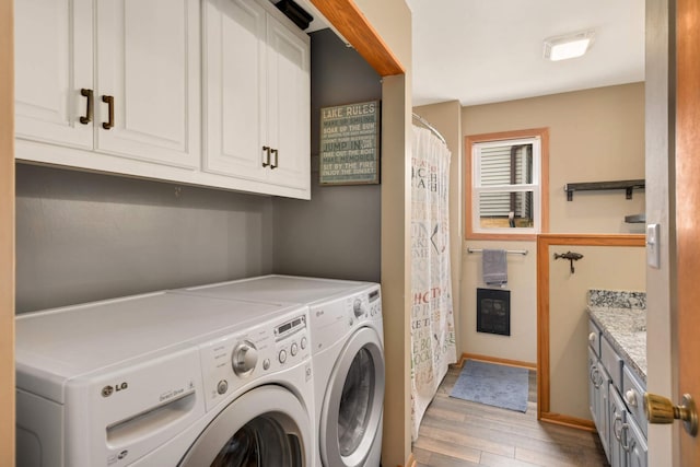 laundry area featuring light wood-type flooring, baseboards, independent washer and dryer, and cabinet space