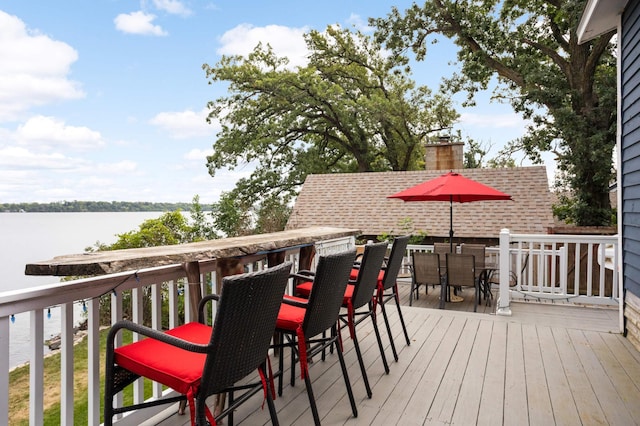 wooden deck with outdoor dining space and a water view