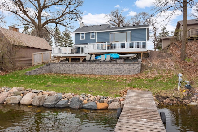 rear view of house with a deck with water view, a shingled roof, and a chimney