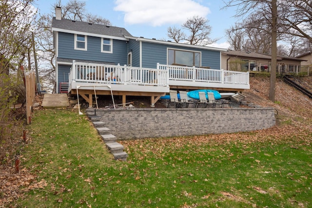 rear view of property with a lawn, a chimney, and a deck
