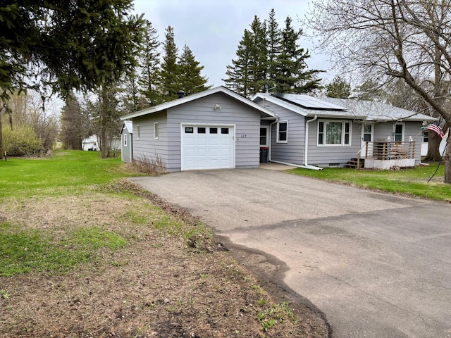 view of front of house with an attached garage, driveway, roof mounted solar panels, and a front lawn