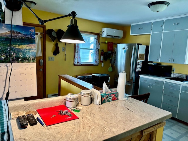 kitchen with light countertops, blue cabinetry, freestanding refrigerator, a wall unit AC, and pendant lighting