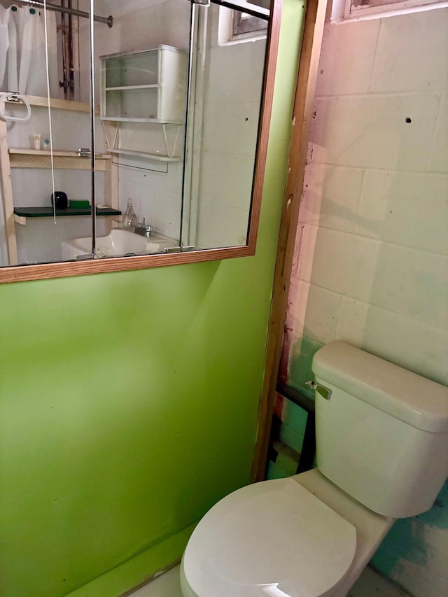bathroom with concrete block wall and toilet