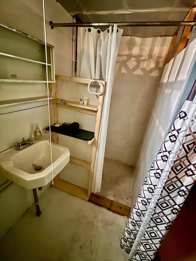 full bathroom with a shower with curtain, a sink, and unfinished concrete floors