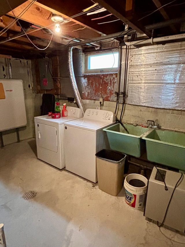 basement featuring separate washer and dryer, a sink, and electric panel