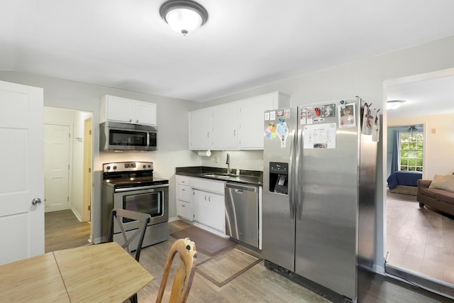 451 Taylor St NE, Minneapolis, MN 55413 - kitchen featuring stainless steel appliances, wood finished floors, white cabinetry, and dark countertops