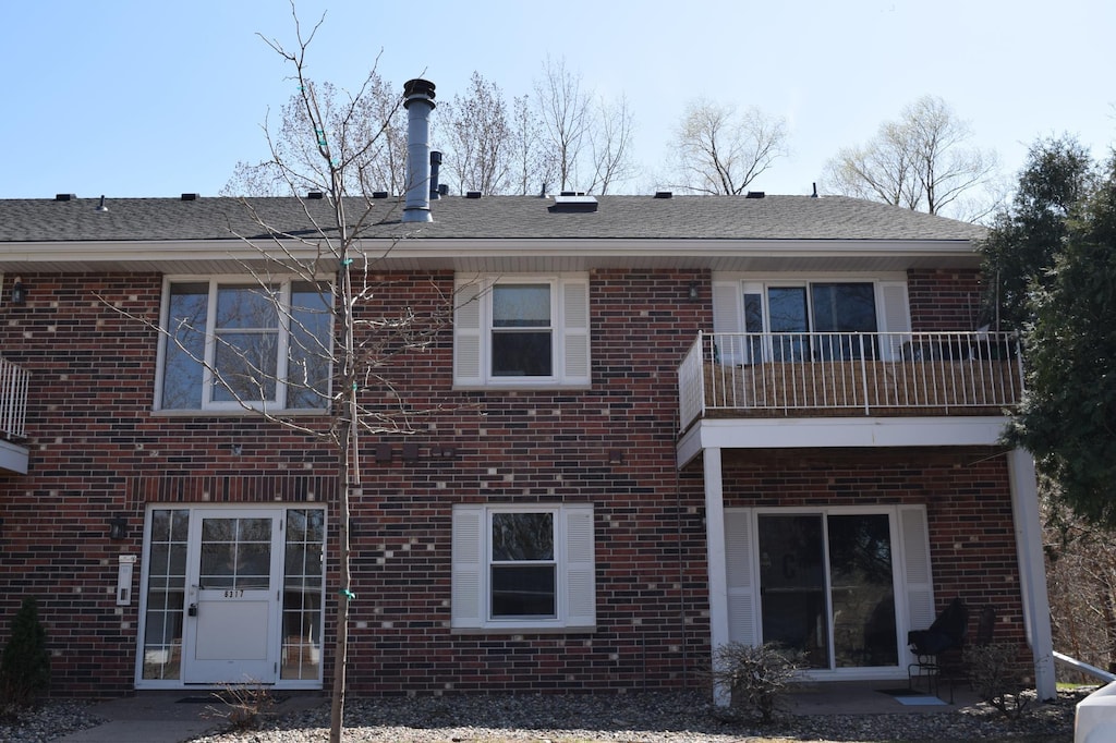 rear view of property featuring a patio area, a balcony, and brick siding
