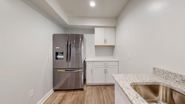 1213 Grey Fox Ave SW, Rochester, MN 55902 - kitchen featuring stainless steel fridge, light wood-type flooring, white cabinets, light stone counters, and a sink