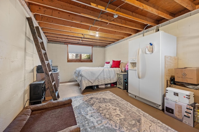 1601 5th Ave, Grand Rapids, MN 55744 - bedroom with concrete block wall, a wood stove, white fridge with ice dispenser, and concrete flooring