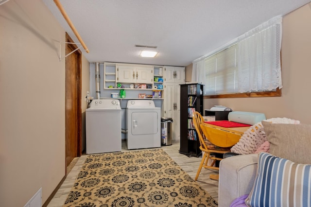 1601 5th Ave, Grand Rapids, MN 55744 - washroom with light wood-style flooring, cabinet space, visible vents, a textured ceiling, and washer and clothes dryer