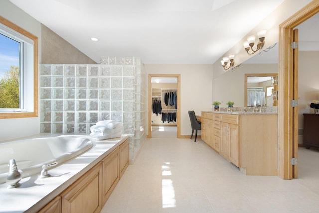 bathroom with a garden tub, a spacious closet, vanity, and tile patterned floors