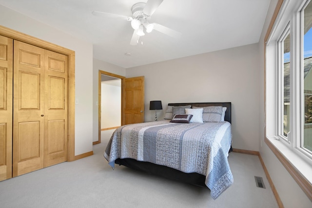 bedroom featuring baseboards, light colored carpet, a ceiling fan, and a closet