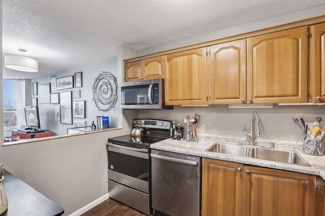 1425 28th St Unit 407, Minneapolis, MN 55408 - kitchen with stainless steel appliances, a sink, a textured ceiling, and dark wood finished floors