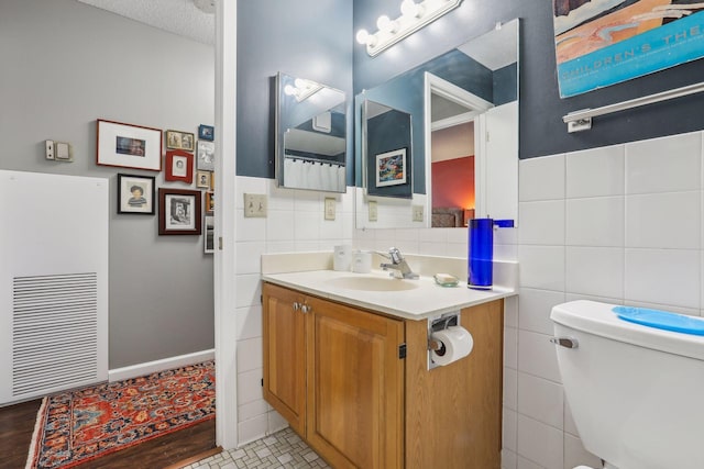 1425 28th St Unit 407, Minneapolis, MN 55408 - bathroom featuring tile walls, vanity, toilet, and a wainscoted wall