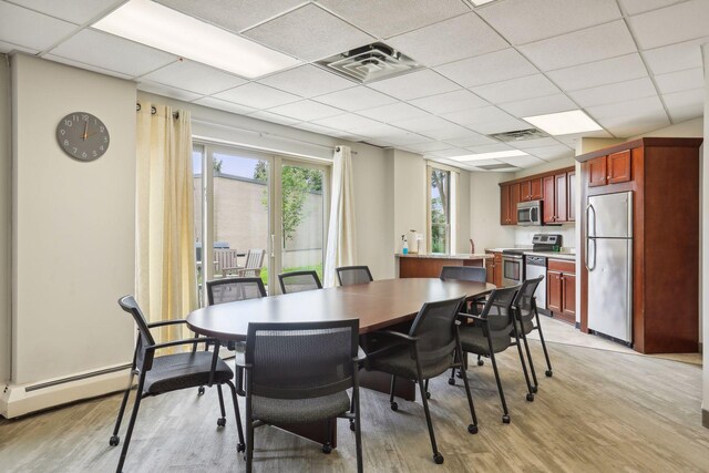 1425 28th St Unit 407, Minneapolis, MN 55408 - dining space with light wood finished floors, a drop ceiling, and a baseboard radiator