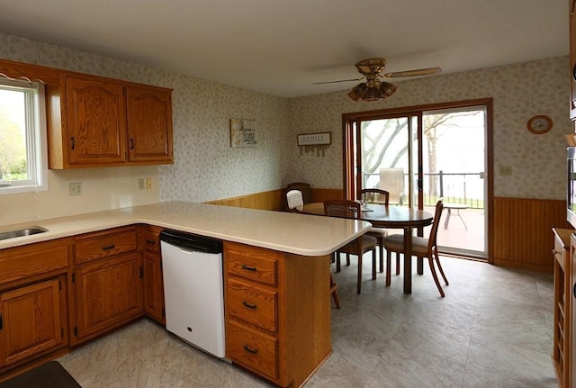 44172 Mosquito Heights Rd, Perham, MN 56573 - kitchen with wallpapered walls, a wainscoted wall, brown cabinetry, a peninsula, and white dishwasher