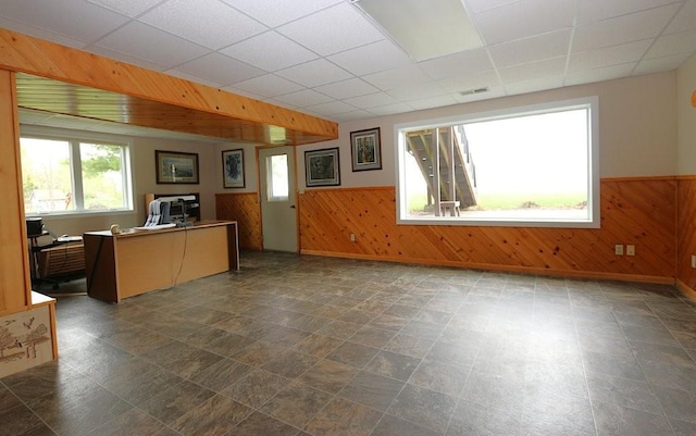 44172 Mosquito Heights Rd, Perham, MN 56573 - unfurnished living room with wooden walls, a wainscoted wall, a drop ceiling, a desk, and baseboards