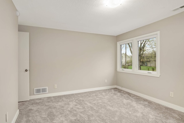 carpeted empty room featuring baseboards and visible vents