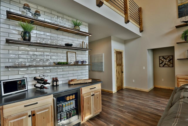 indoor dry bar featuring beverage cooler, dark wood finished floors, and baseboards