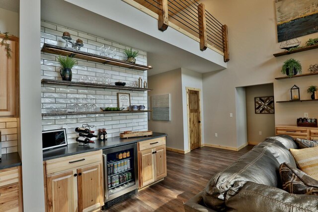 indoor dry bar with beverage cooler, dark wood-style floors, and baseboards