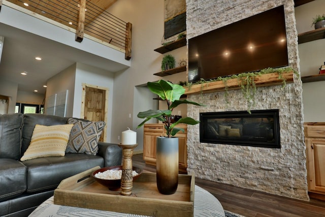 living room featuring wood finished floors, a stone fireplace, a high ceiling, and recessed lighting