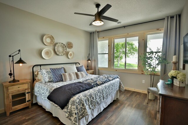 bedroom featuring baseboards, dark wood finished floors, ceiling fan, and a textured ceiling