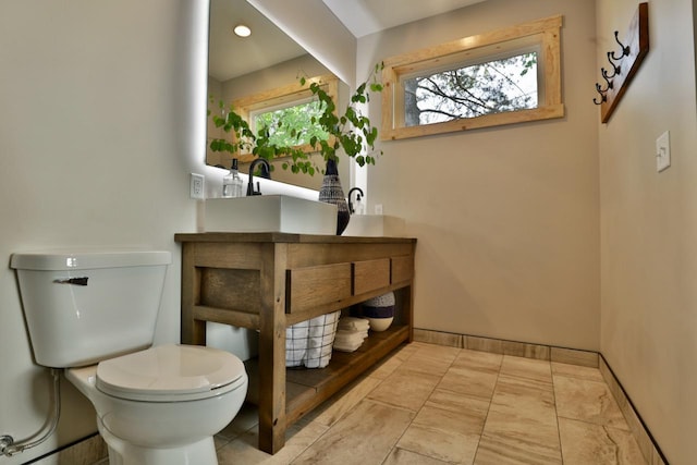 bathroom with toilet, vanity, and baseboards