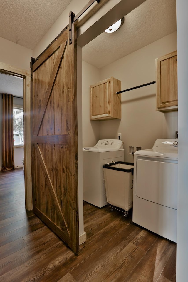 washroom with cabinet space, separate washer and dryer, a barn door, dark wood-style flooring, and a textured ceiling