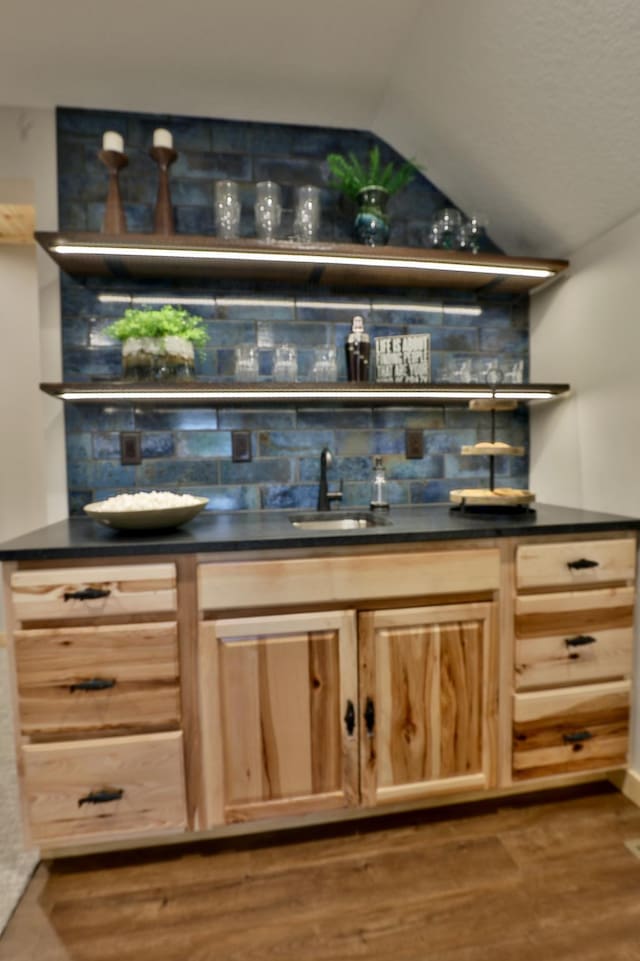 indoor wet bar with decorative backsplash, dark wood-type flooring, and vaulted ceiling