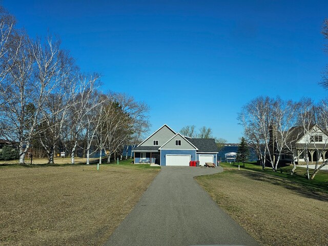 traditional-style home with asphalt driveway, a garage, and a front yard