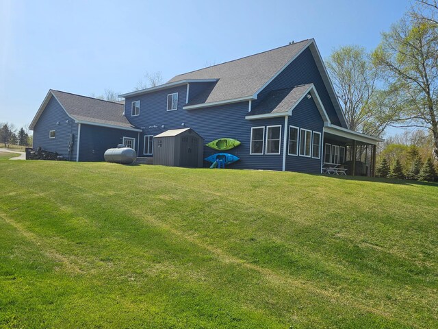 back of house with a shed, a sunroom, a lawn, and an outdoor structure