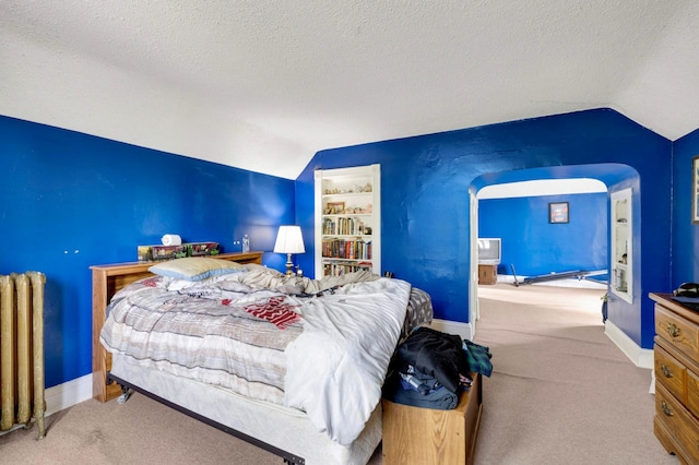 1102 Pacific St, Saint Paul, MN 55106 - carpeted bedroom featuring vaulted ceiling, radiator, a textured ceiling, arched walkways, and baseboards