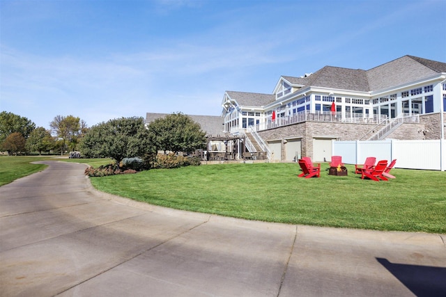 exterior space featuring a lawn, a shingled roof, an outdoor fire pit, fence, and stairs