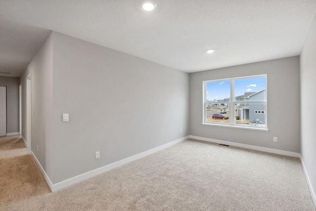 unfurnished room featuring recessed lighting, baseboards, a textured ceiling, and light colored carpet