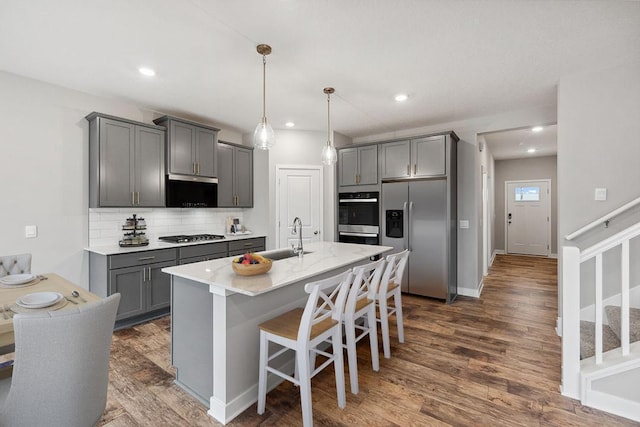 kitchen with tasteful backsplash, a sink, a breakfast bar area, appliances with stainless steel finishes, and gray cabinetry