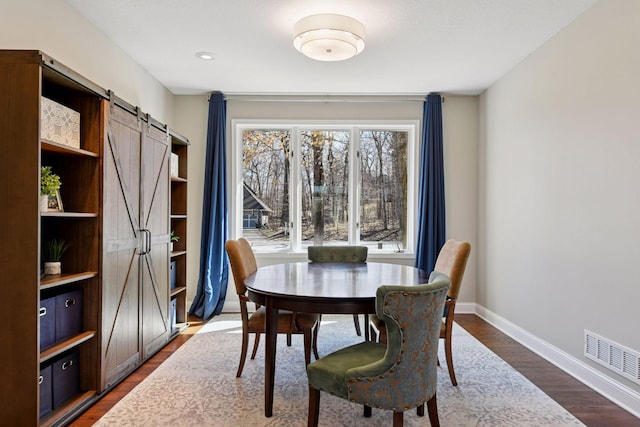 5610 Burl Oaks Ct, Minnetrista, MN 55364 - dining area with a barn door, baseboards, and dark wood-style floors