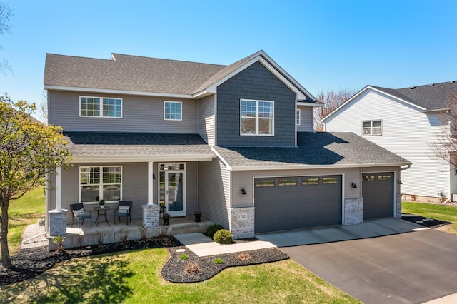 craftsman house with a porch, a front lawn, roof with shingles, and aphalt driveway
