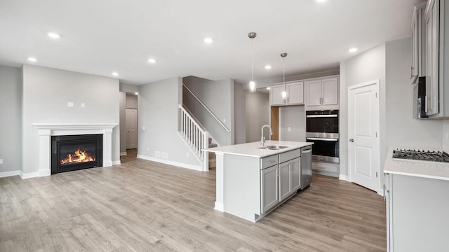 kitchen featuring appliances with stainless steel finishes, light wood-type flooring, recessed lighting, and a sink