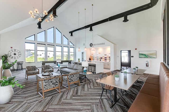 dining space featuring carpet, track lighting, high vaulted ceiling, and a notable chandelier
