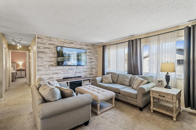 living area featuring an accent wall, light carpet, and a textured ceiling