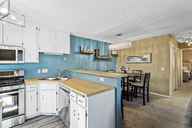 kitchen with a sink, white cabinets, stainless steel appliances, and a peninsula