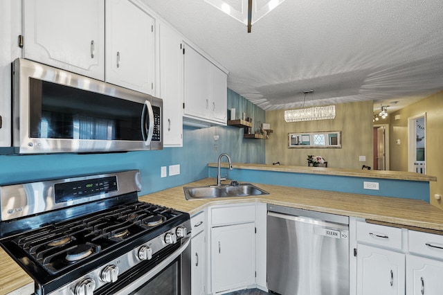 kitchen with white cabinets, appliances with stainless steel finishes, a sink, light countertops, and a textured ceiling