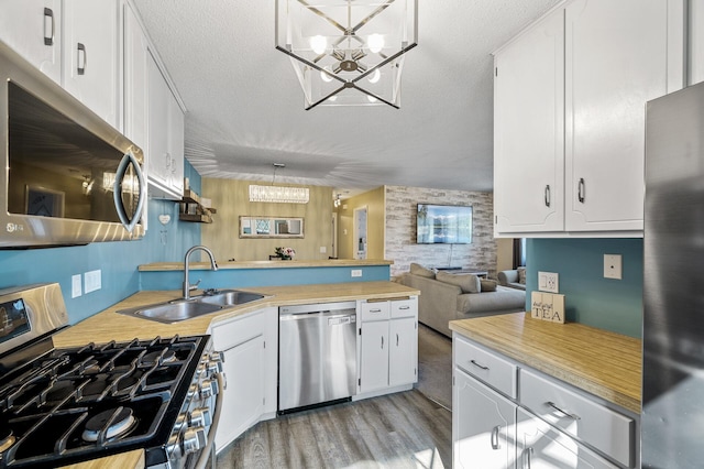 kitchen with a sink, an inviting chandelier, stainless steel appliances, and a peninsula