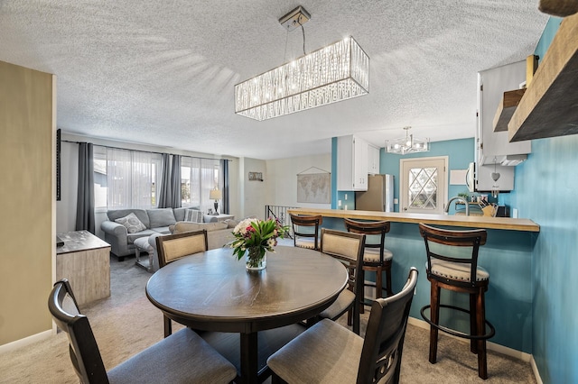 dining space with carpet floors, baseboards, a textured ceiling, and a chandelier