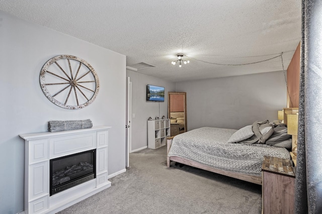 bedroom with a textured ceiling, a glass covered fireplace, and light carpet