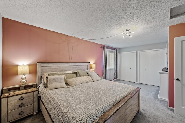 bedroom with carpet floors, a textured ceiling, and multiple closets