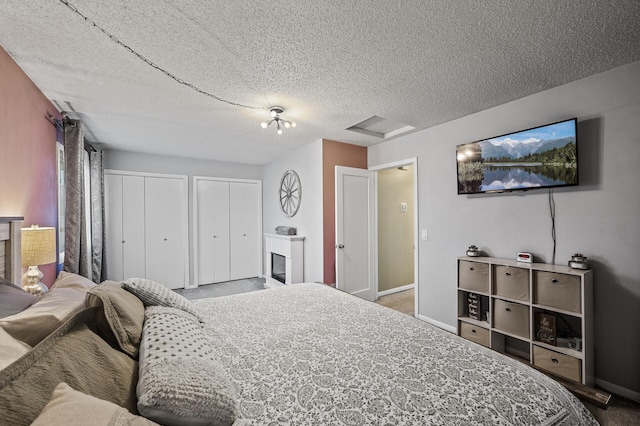 carpeted bedroom featuring two closets, a textured ceiling, and baseboards